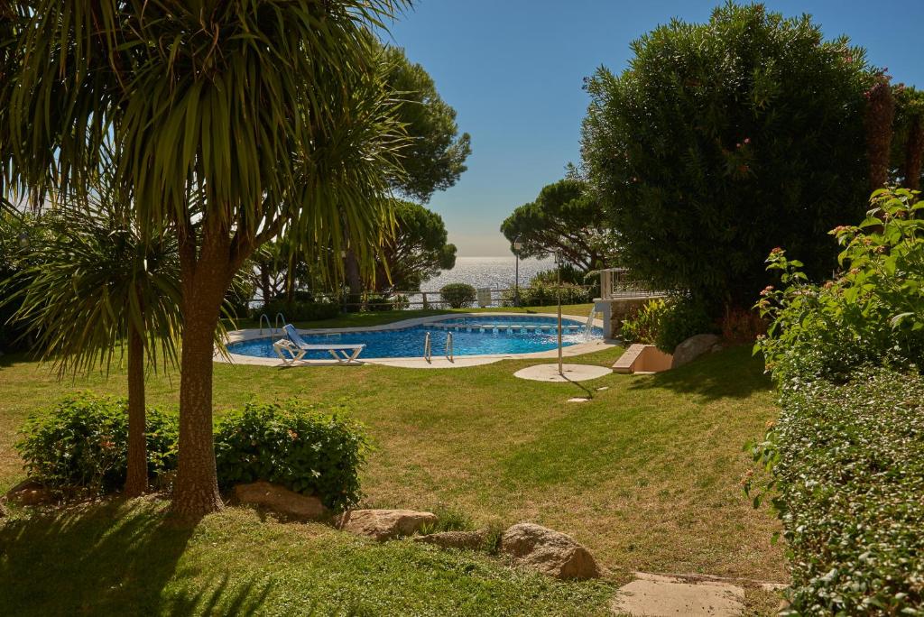 a swimming pool in a yard with a palm tree at Residence Velas Garden Pool Suite in S'Agaro