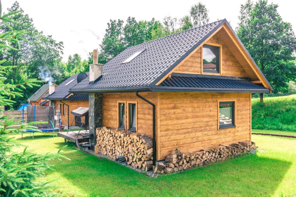 a log cabin with a pile of fire wood at Domki na Łazach in Uherce Mineralne (7)
