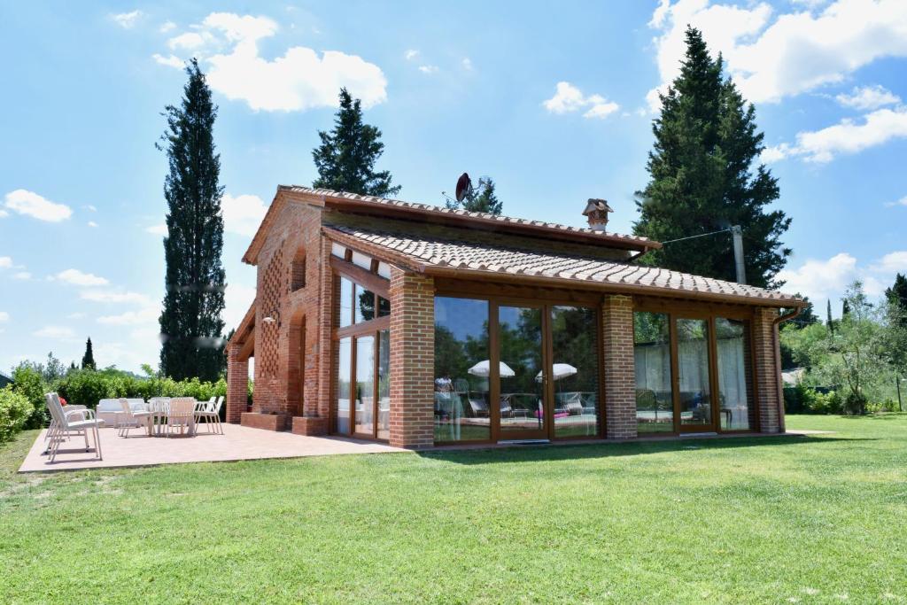San Giovanni a Corazzano にあるFienile Il Noceの芝生の上にコンサバトリーを設けたレンガ造りの家