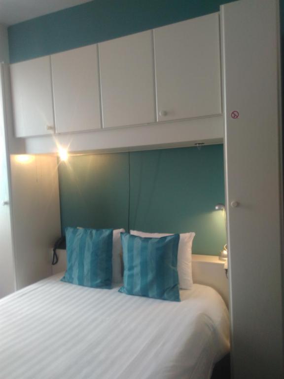 a bedroom with a bed with blue pillows and white cabinets at Eurotel in Liège