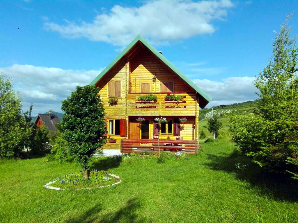 a wooden house in a field with a tree at Sunnyside in Žabljak