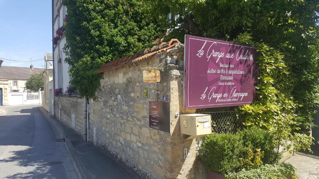 un bâtiment avec un panneau violet sur son côté dans l'établissement La Grange en Champagne, à Hermonville