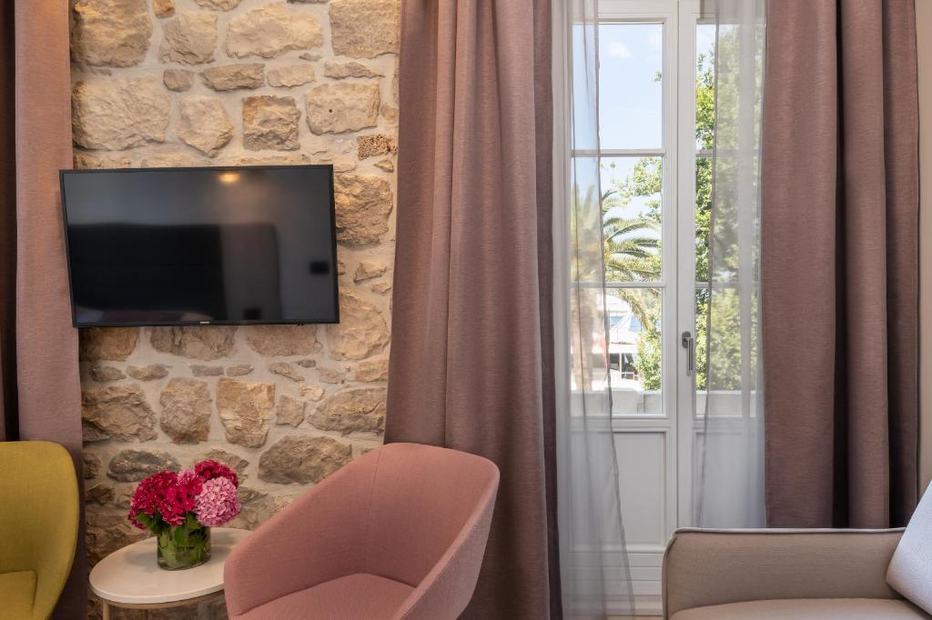 ein Wohnzimmer mit einem TV an einer Steinmauer in der Unterkunft Boutique B&B Villa Faggioni in Cavtat