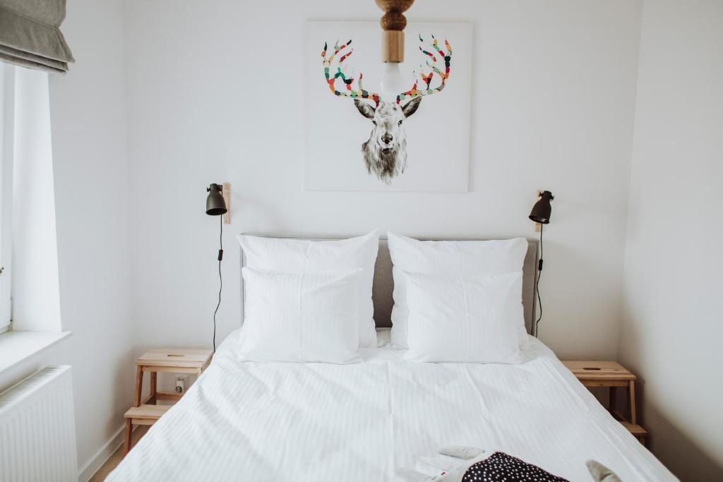 a bedroom with a bed with white sheets and a heart on the wall at Śpij w Nysie Apartments in Nysa