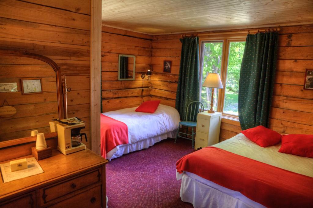 a bedroom with two beds in a log cabin at Auberge Cap au Leste in Sainte-Rose-du-Nord