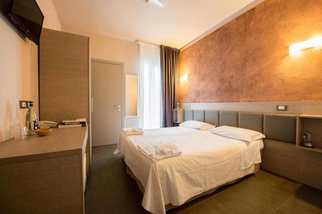 ein Hotelzimmer mit einem weißen Bett in einem Zimmer in der Unterkunft Hotel Helvetia in Lido di Jesolo
