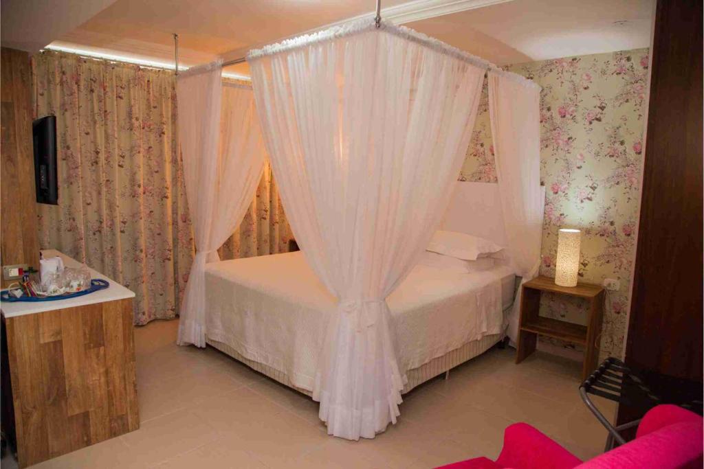 a bedroom with a canopy bed with white curtains at Royal Plaza Hotel in Apucarana