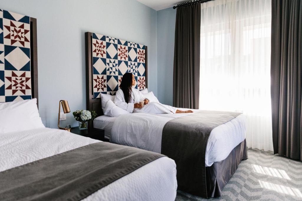 a woman in a hotel room with two beds at Mount Royal Hotel in Banff