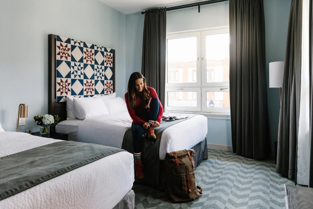 a woman sitting on a bed in a hotel room at Mount Royal Hotel in Banff