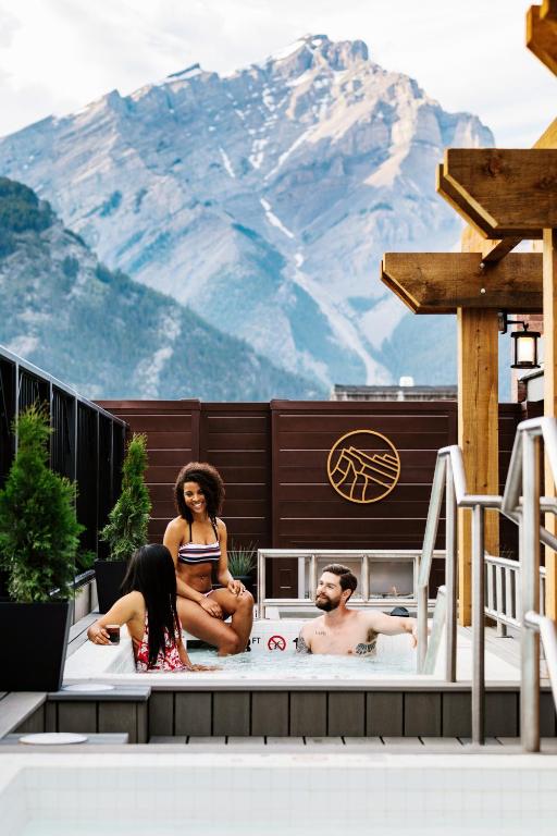 a group of people sitting in a hot tub with a mountain at Mount Royal Hotel in Banff