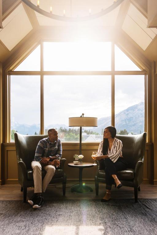 a man and woman sitting in chairs in front of a window at Mount Royal Hotel in Banff