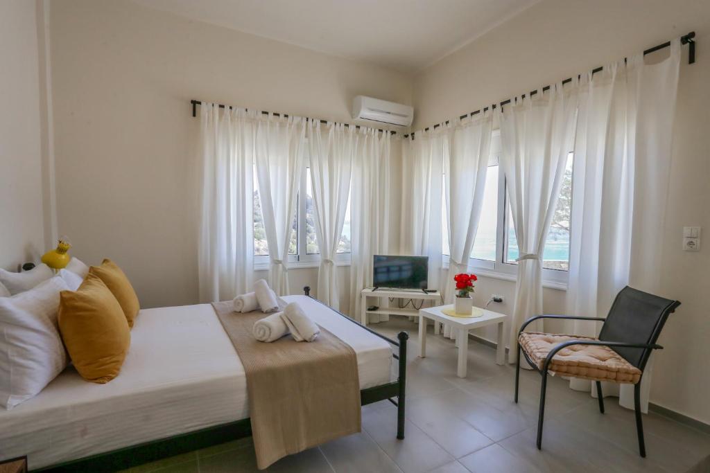 a bedroom with a bed and a chair and windows at Skouros Villa in Kastrí