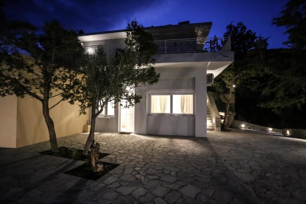 a white house with a tree in front of it at Skouros Villa in Kastrí