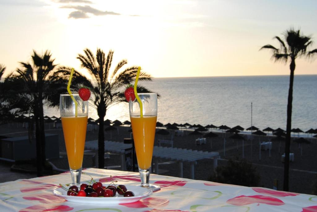 dos vasos de zumo de naranja y un bol de fruta en una mesa en Frente al mar, en Fuengirola