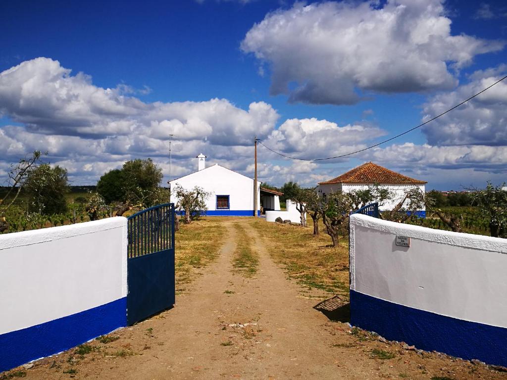 een onverharde weg met een hek en een wit gebouw bij Monte dos Velhos in Reguengos de Monsaraz