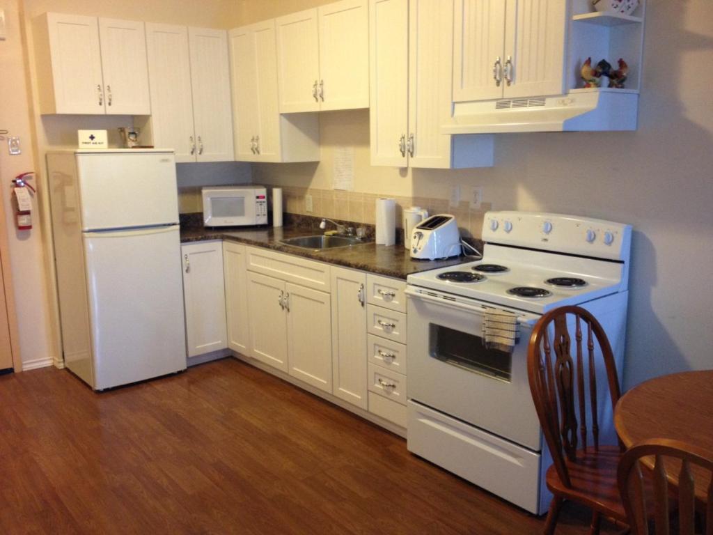 een keuken met een wit fornuis en een koelkast bij Ashton Apartments in St. John's