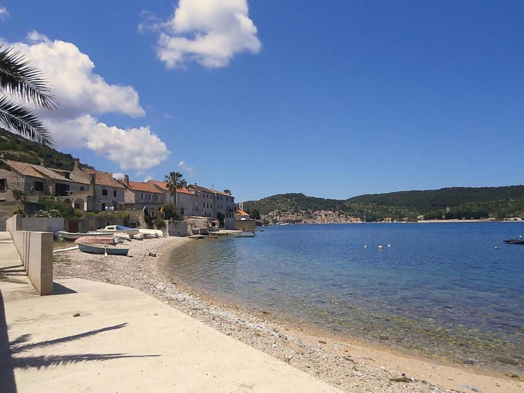 a beach with boats on the water and buildings at Apartman Prošperino in Vis