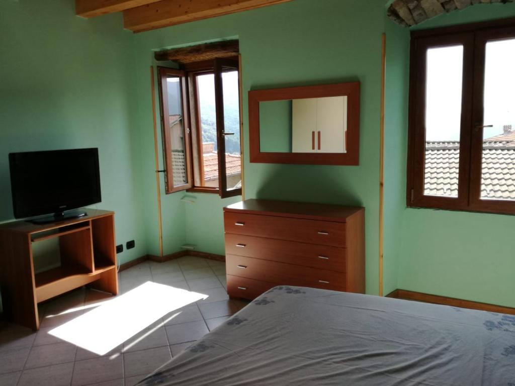 1 dormitorio con 1 cama, TV y ventanas en casa tarcisio, en Faggeto Lario 