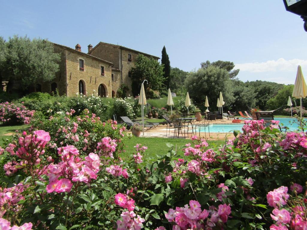 um jardim com flores cor-de-rosa e uma piscina em EcoResort Il Cantico della Natura em Magione