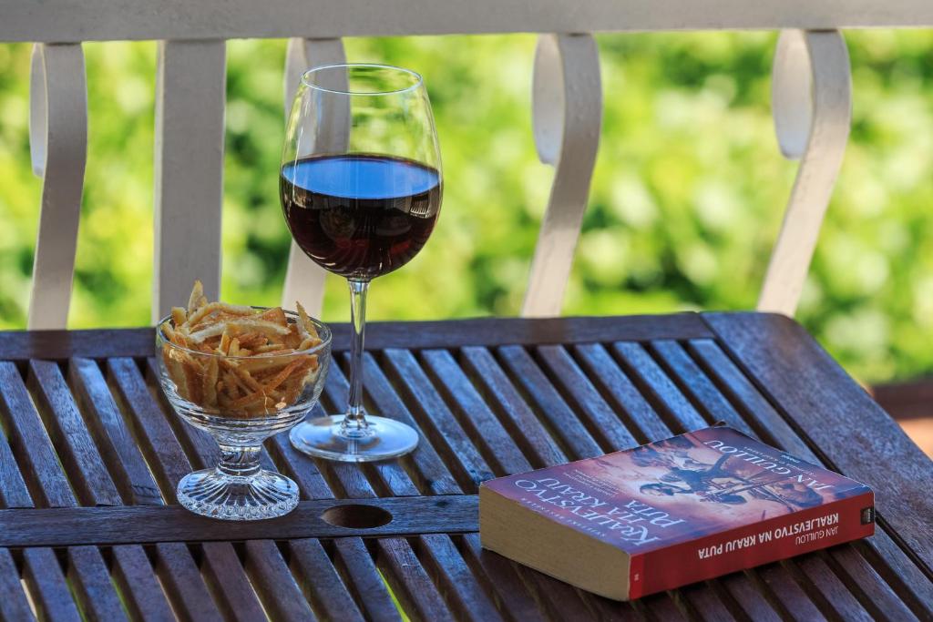 a glass of wine and a book on a wooden table at Apartman Prošperino in Vis