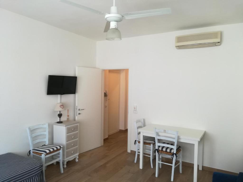 a room with a white table and chairs and a tv at Casetta Mare in Castiglione della Pescaia