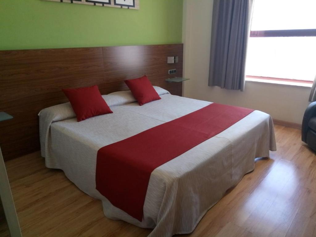 een slaapkamer met een groot bed met rode kussens bij Olimpia Hoteles in Totana