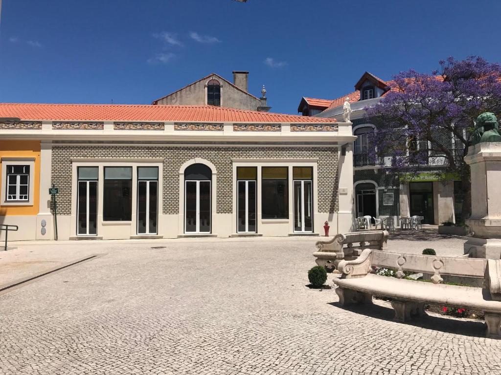 un grand bâtiment en briques avec un banc devant lui dans l'établissement Wood Steel & Glass, à Marinha Grande