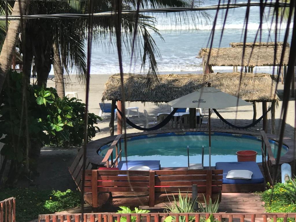 una piscina con sombrilla y una playa en Casa de las Olas Surf & Beach Club en Acapulco