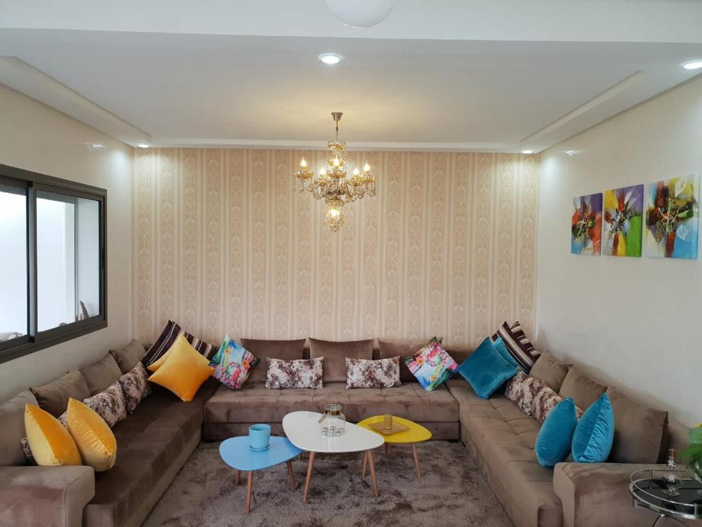 a living room with a couch with colorful pillows at Villa Blanca Beach Pieds-Sur-Mer in Sidi Rahal