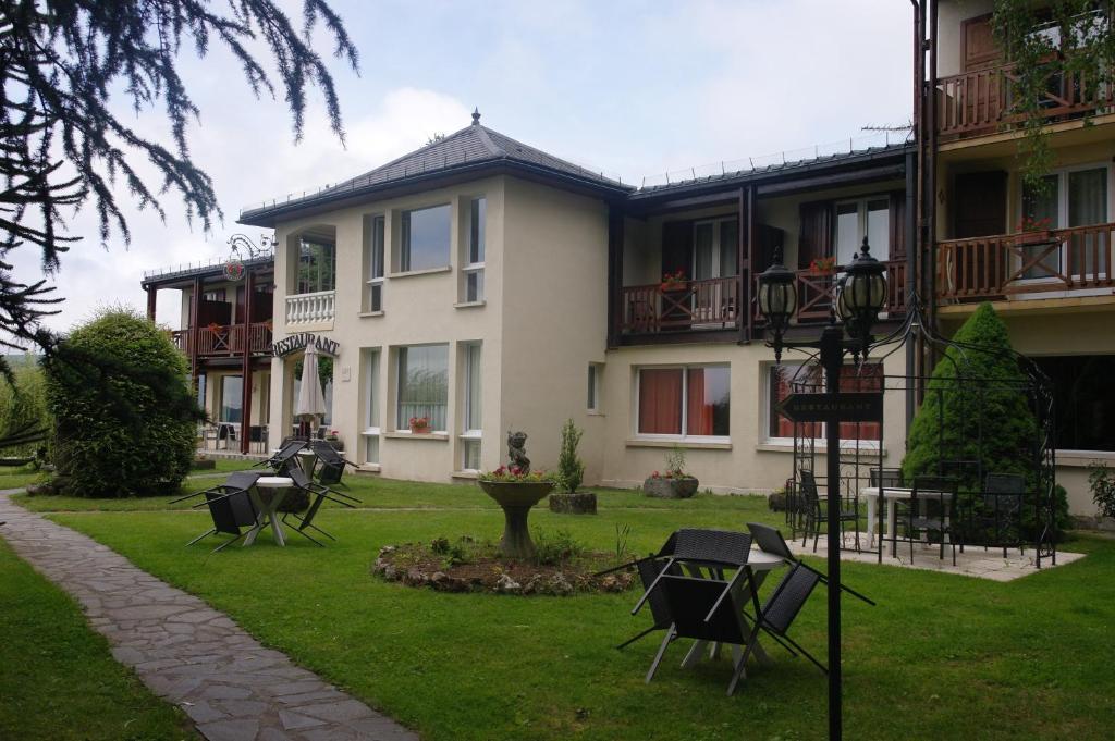 un bâtiment avec des chaises dans l'herbe devant lui dans l'établissement Hostellerie Saint Clément, à Vic-sur-Cère