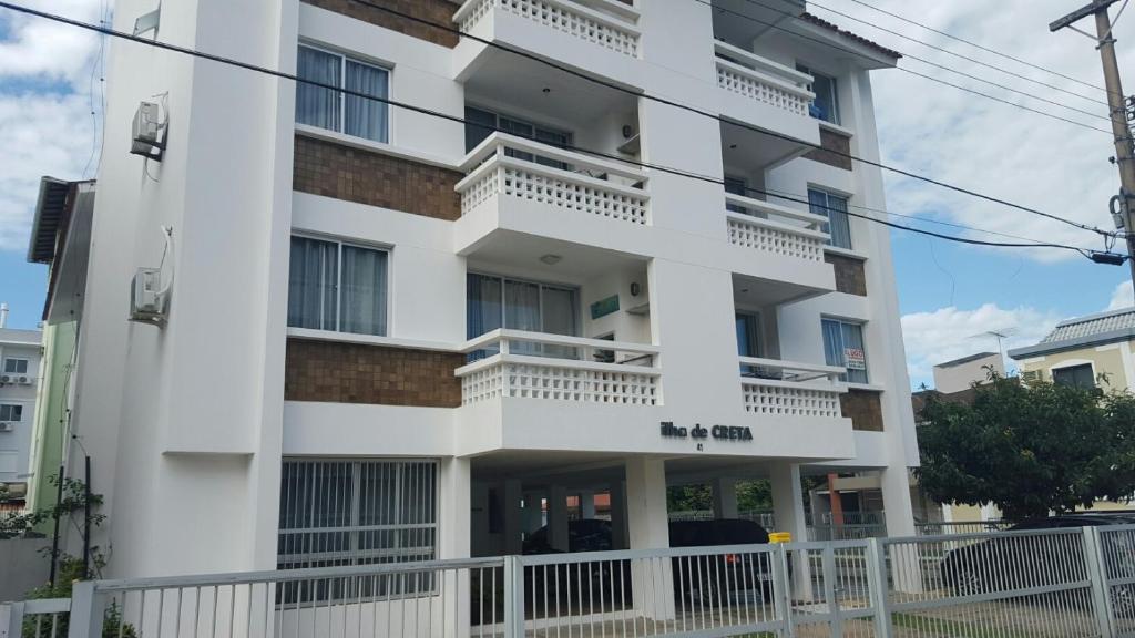 un edificio blanco con balcones y una valla en CRETA 101 1 Andar, en Florianópolis