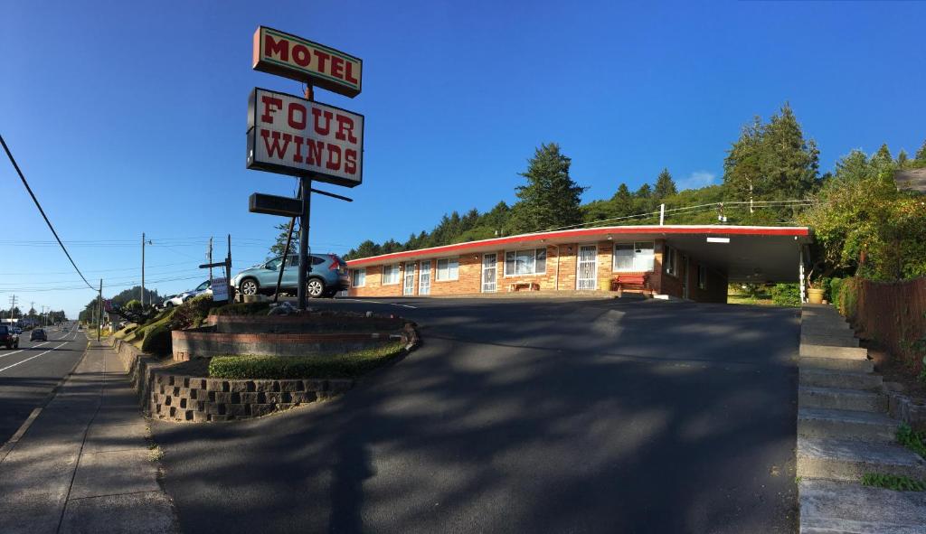 a sign for a hotel next to a building at Four Winds Motel in Depoe Bay