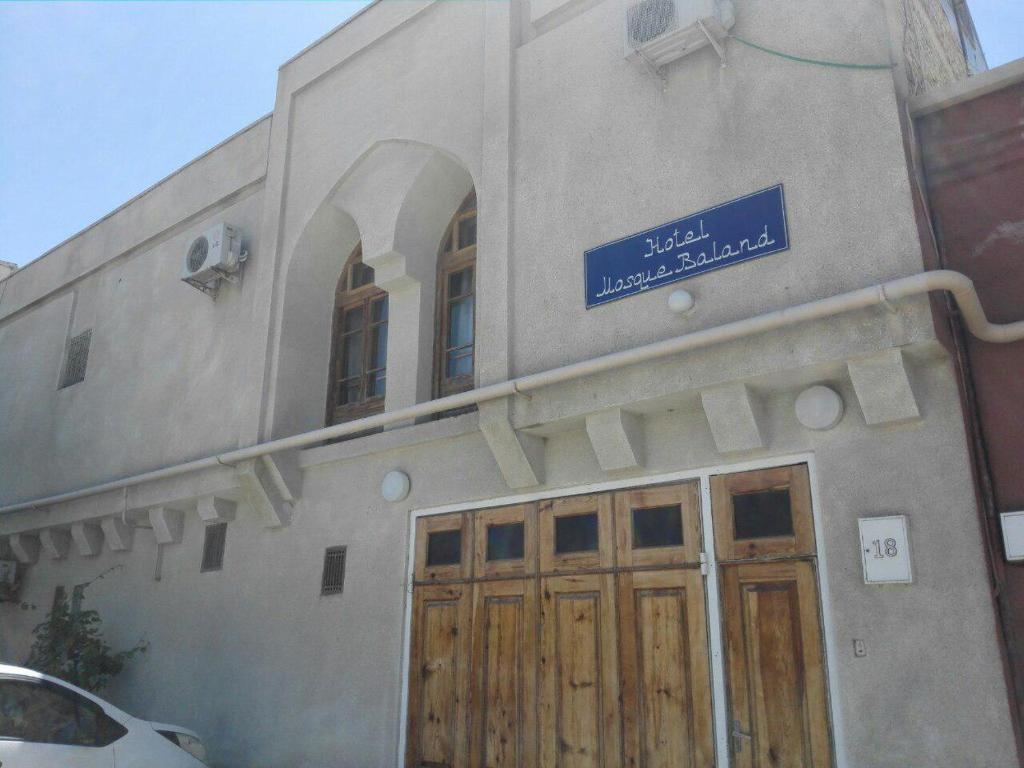 a building with wooden doors and a blue sign on it at Hotel Mosque Baland in Bukhara