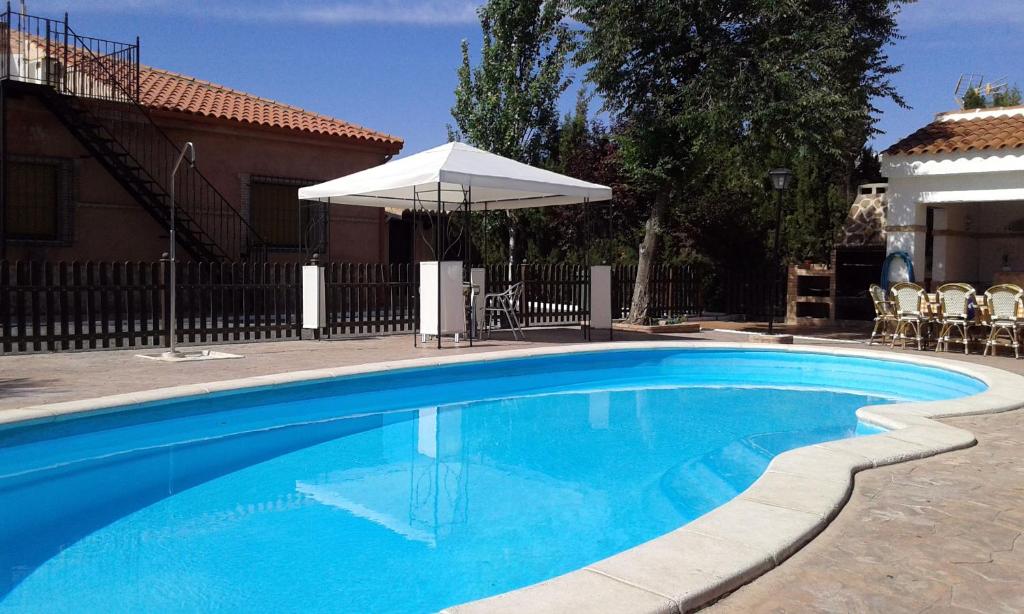 una gran piscina azul con sombrilla en Casa rural con piscina y pista de padel - Casa de Pacas, en Bolaños de Calatrava