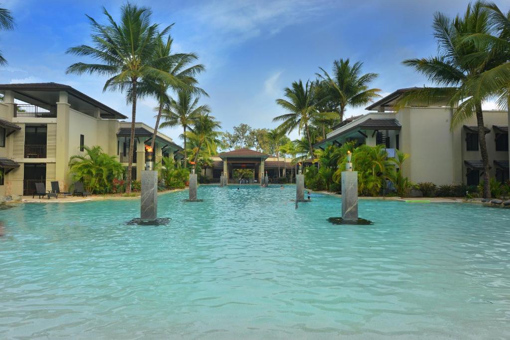 a large swimming pool with palm trees and buildings at Seascape Holidays at Seascape Temple in Port Douglas