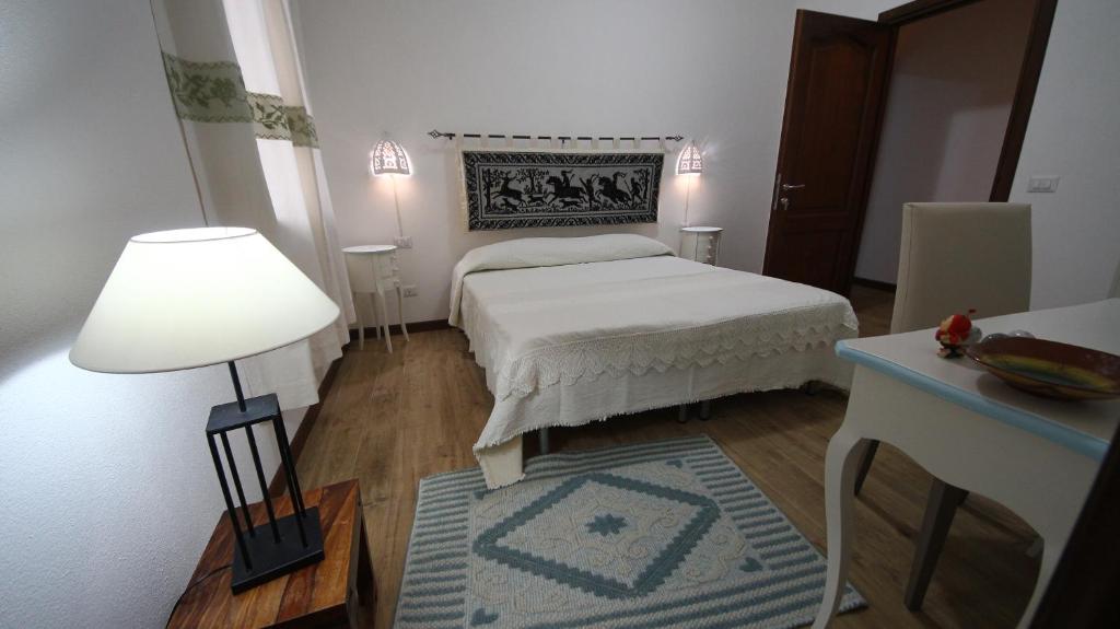 a bedroom with a bed and a table and a lamp at Affittacamere Sa Mariola in Sorgono