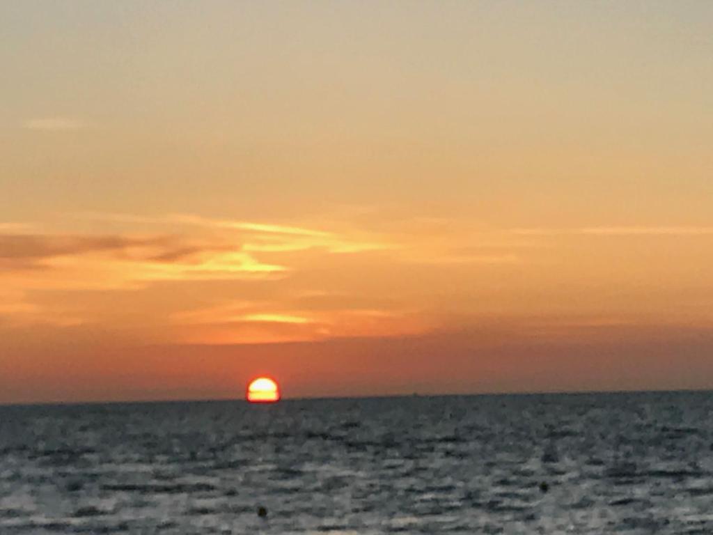 un coucher de soleil sur l'océan et le soleil à l'horizon dans l'établissement La Villersoise - Grand studio 4 personnes, à Villers-sur-Mer