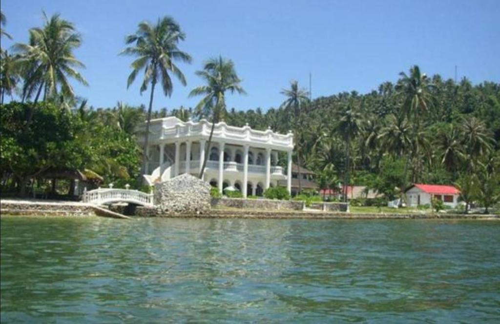 a large white house on the shore of a body of water at Blue Crystal Beach Resort in Puerto Galera