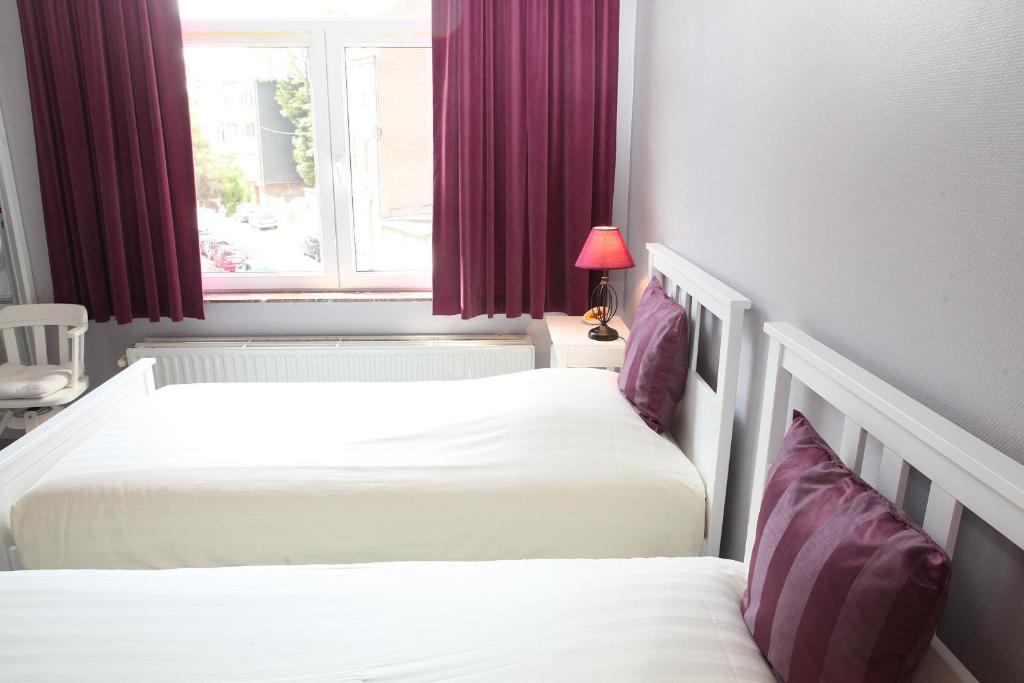 two beds in a room with a window at Eurotel in Liège
