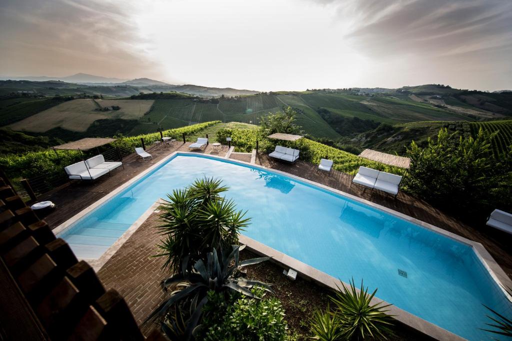 einen Blick über einen Pool mit Stühlen und Bäumen in der Unterkunft Casali Costadoro in Acquaviva Picena