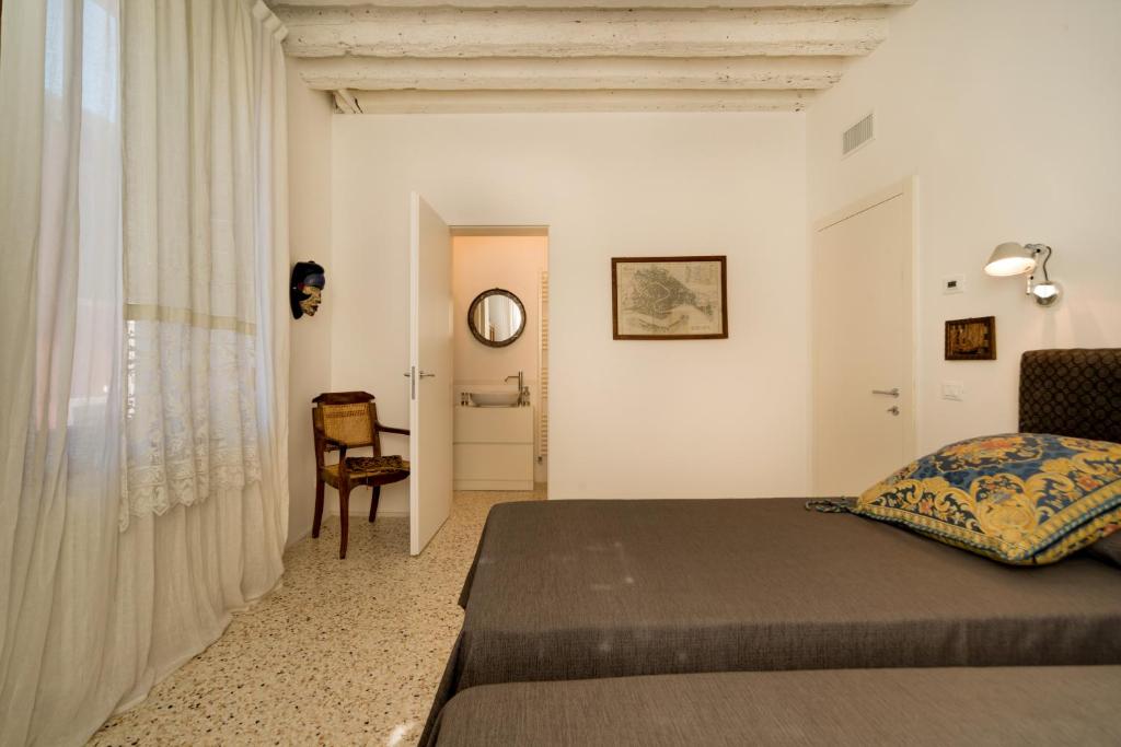 a bedroom with a bed and a chair in a room at Ca' Dorina Luxury in Venice