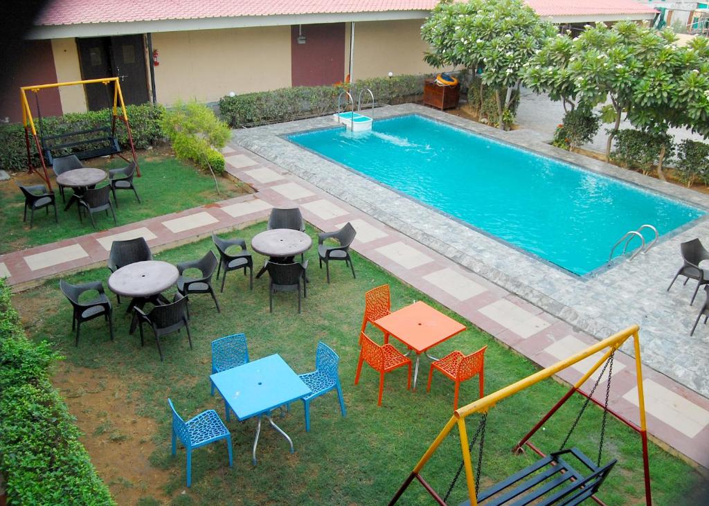 an overhead view of a pool with tables and chairs at JPS Resort with Swimming Pool Near IMT Manesar in Gurgaon