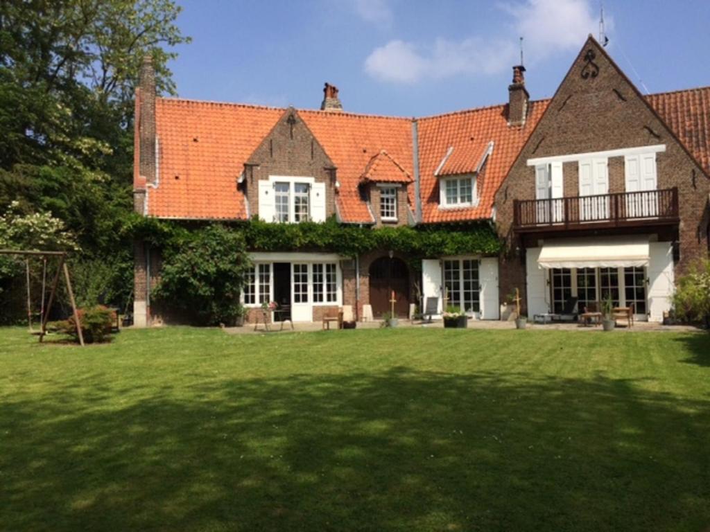 ein großes Haus mit einem Hof mit grünem Gras in der Unterkunft Le Pigeonnier, maison d'hôtes et Spa in Croix