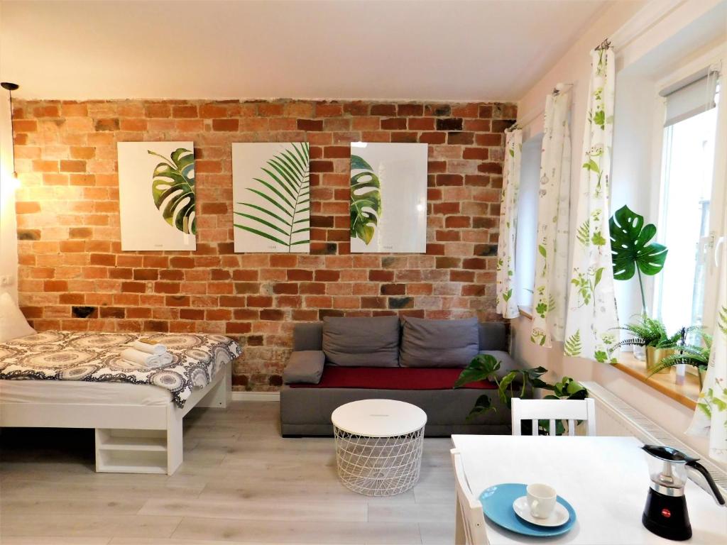 een woonkamer met een bank en een bakstenen muur bij Apartament Egzotyczny in Toruń