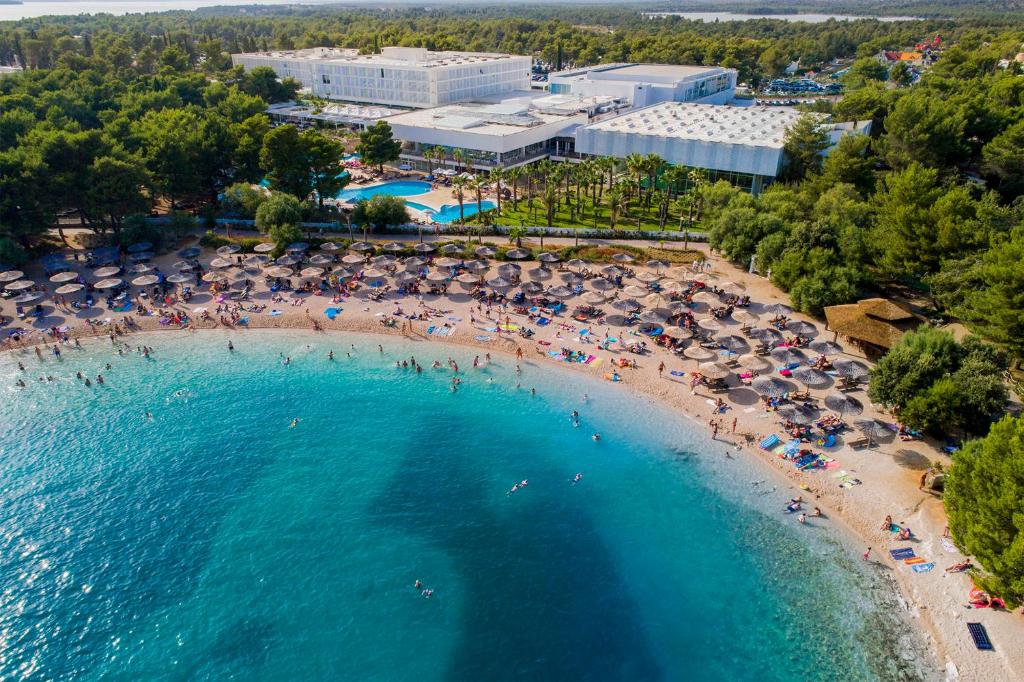 eine Luftansicht auf einen Strand mit Menschen und Sonnenschirmen in der Unterkunft Amadria Park Ivan in Šibenik