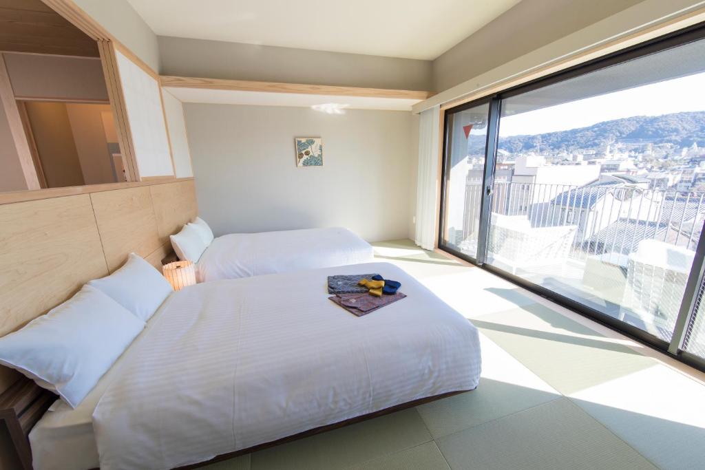 a hotel room with two beds and a large window at My K House in Kyoto