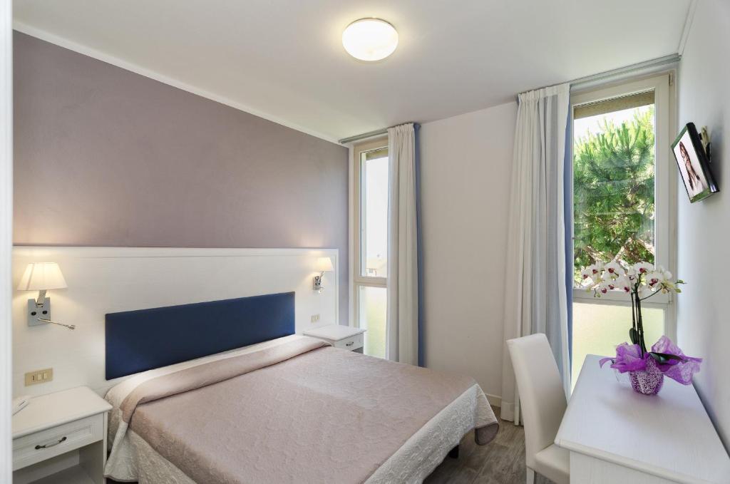 a bedroom with a bed and a desk and a window at Hotel Il Caravaggio in Marina di Pietrasanta