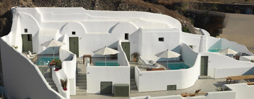 a cluster of white buildings with tables and chairs at Drops Cave Houses in Vóthon
