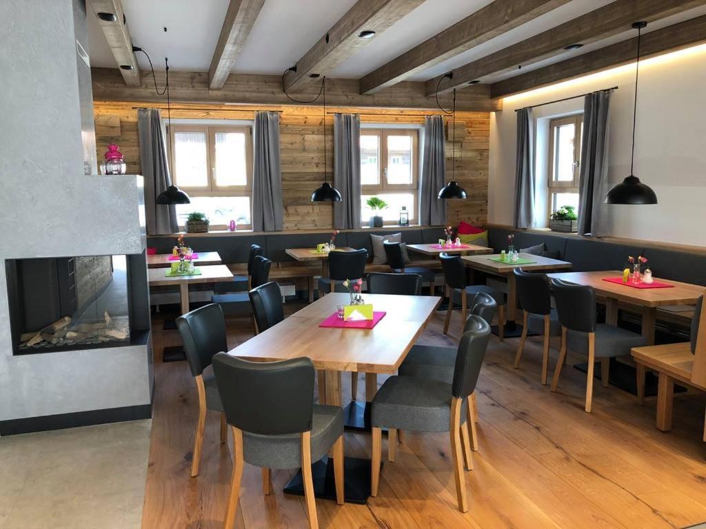 een restaurant met houten tafels en stoelen en een open haard bij Stücklhof Eurasburg in Eurasburg