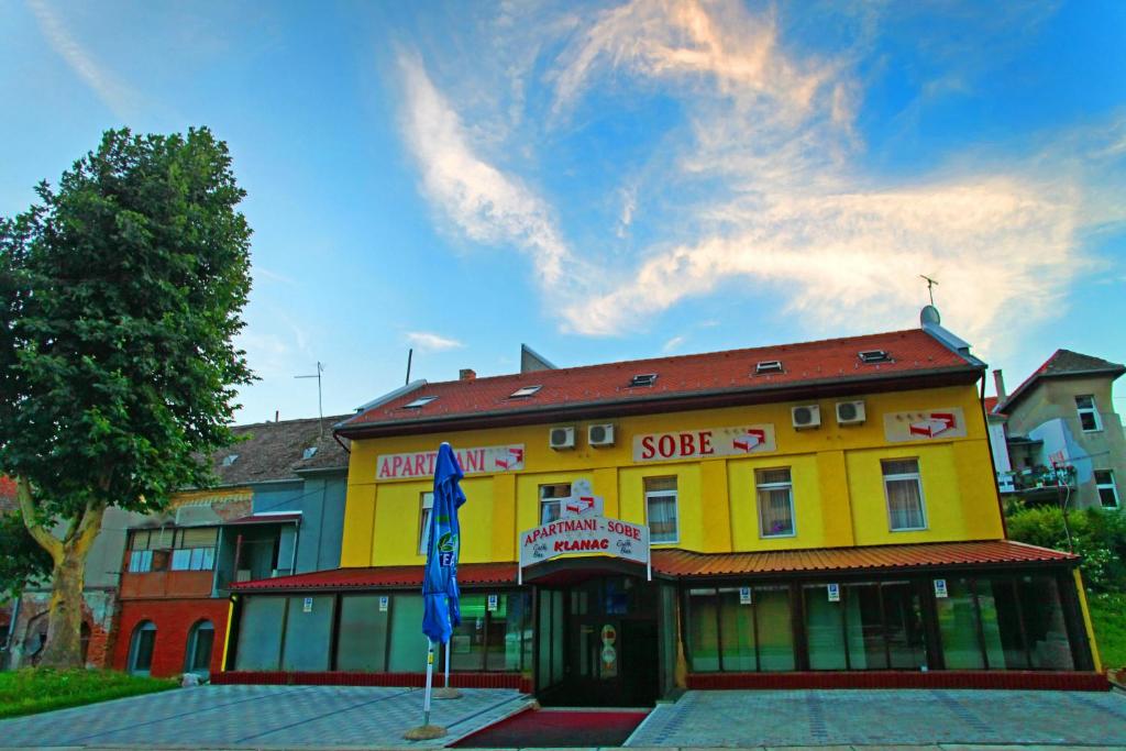 un edificio amarillo con una bandera delante de él en Apartments Klanac, en Osijek